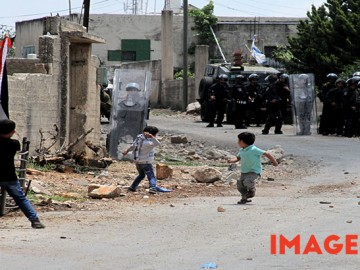 A Palestinian boys throws stones at Israeli soldiers during a protest against the expanding of Jewish settlements in Kufr Qadoom village near the West Bank city of Nablus, on May 15, 2015. Mohammed Turabi.