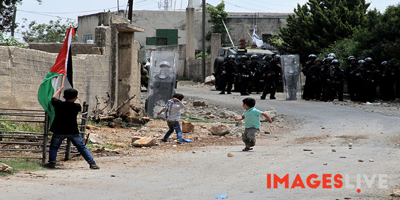 A Palestinian boys throws stones at Israeli soldiers during a protest against the expanding of Jewish settlements in Kufr Qadoom village near the West Bank city of Nablus, on May 15, 2015. Mohammed Turabi.