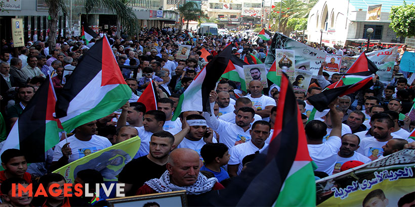 Palestinians hold pictures of Palestinians detained in Israeli prisons during a demonstration to mark Palestinian Prisoner Day in the West Bank city of Nablus on April 17, 2016. (Mohammed Turabi).